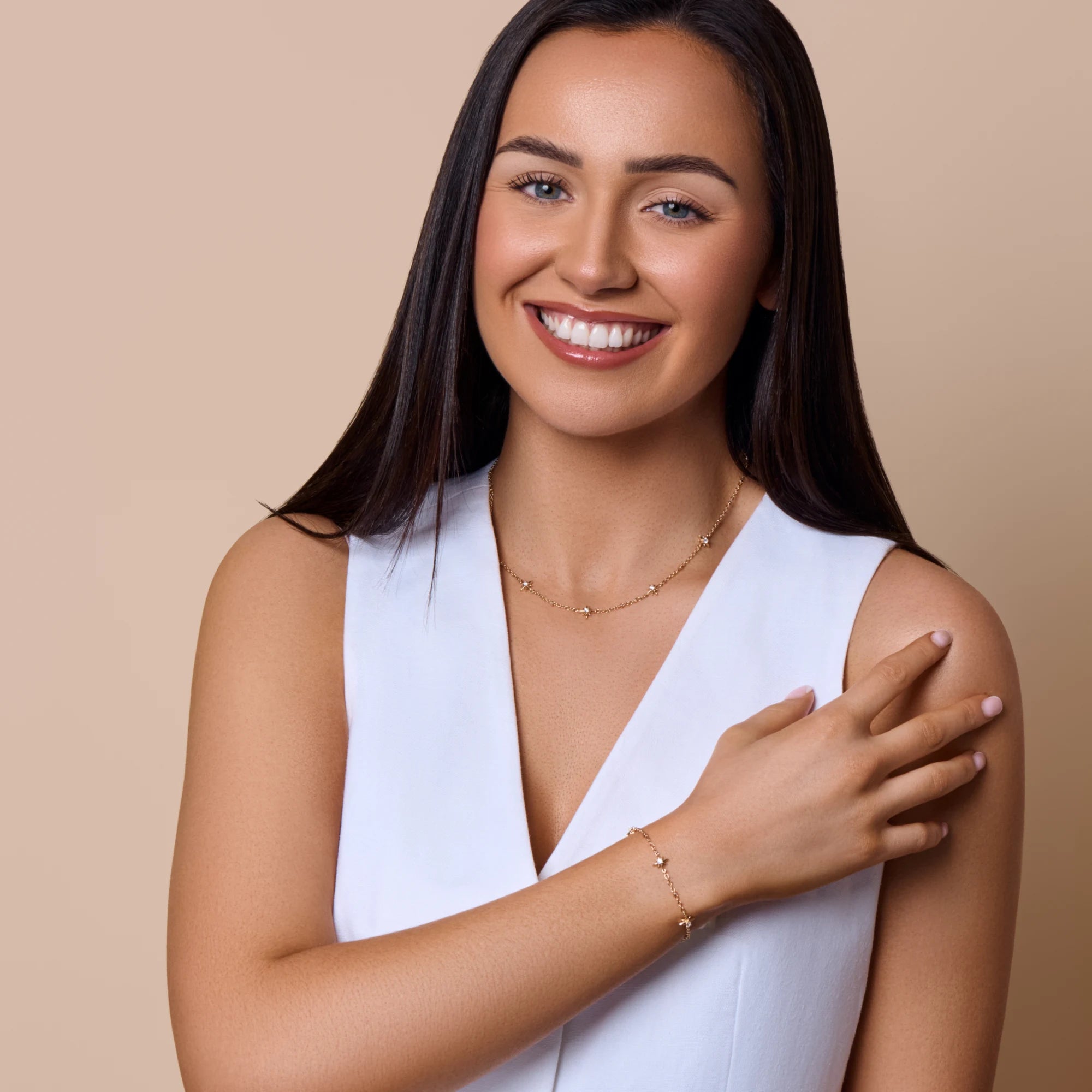 Woman wearing a white sleeveless top against a beige background