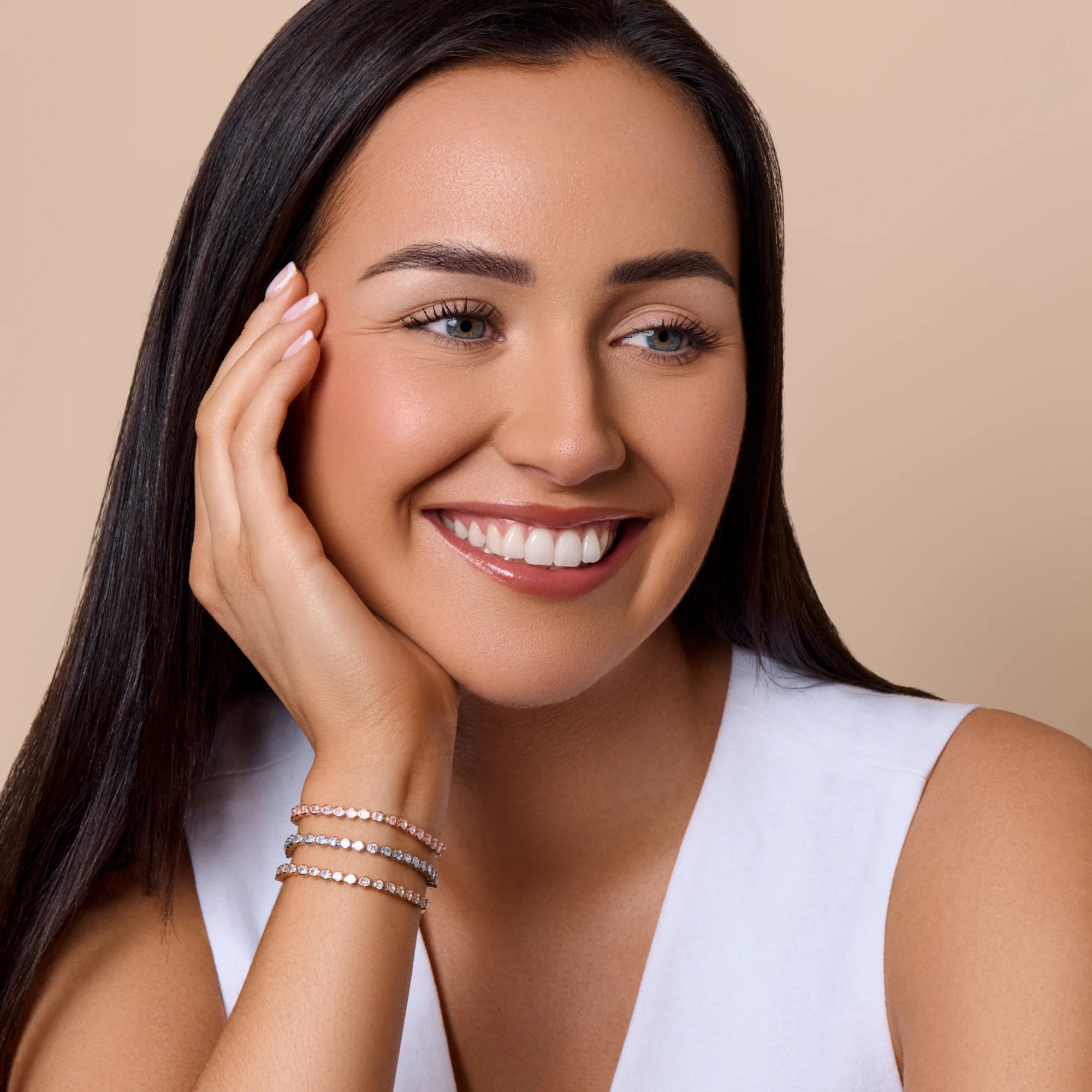 Woman with a radiant smile and hand on face against a beige background
