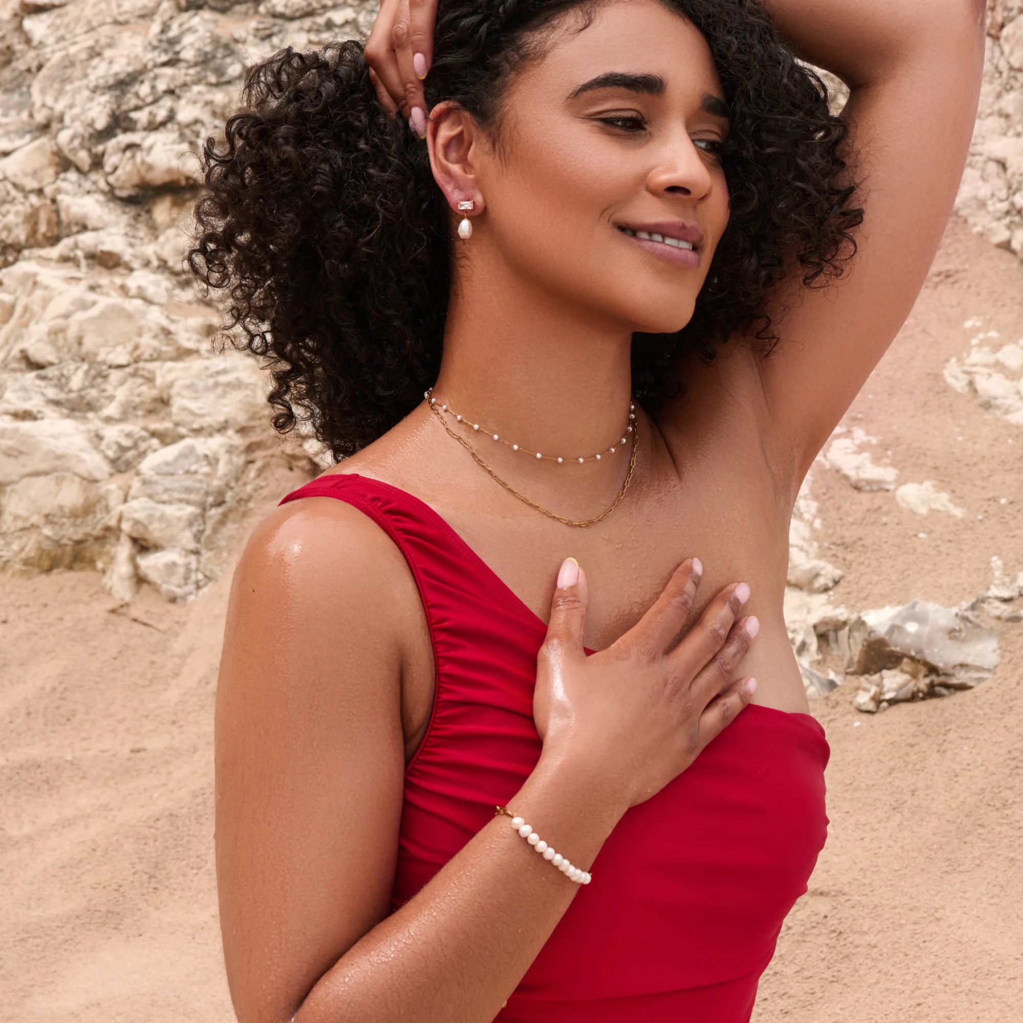 Woman in a red dress standing on a rocky beach