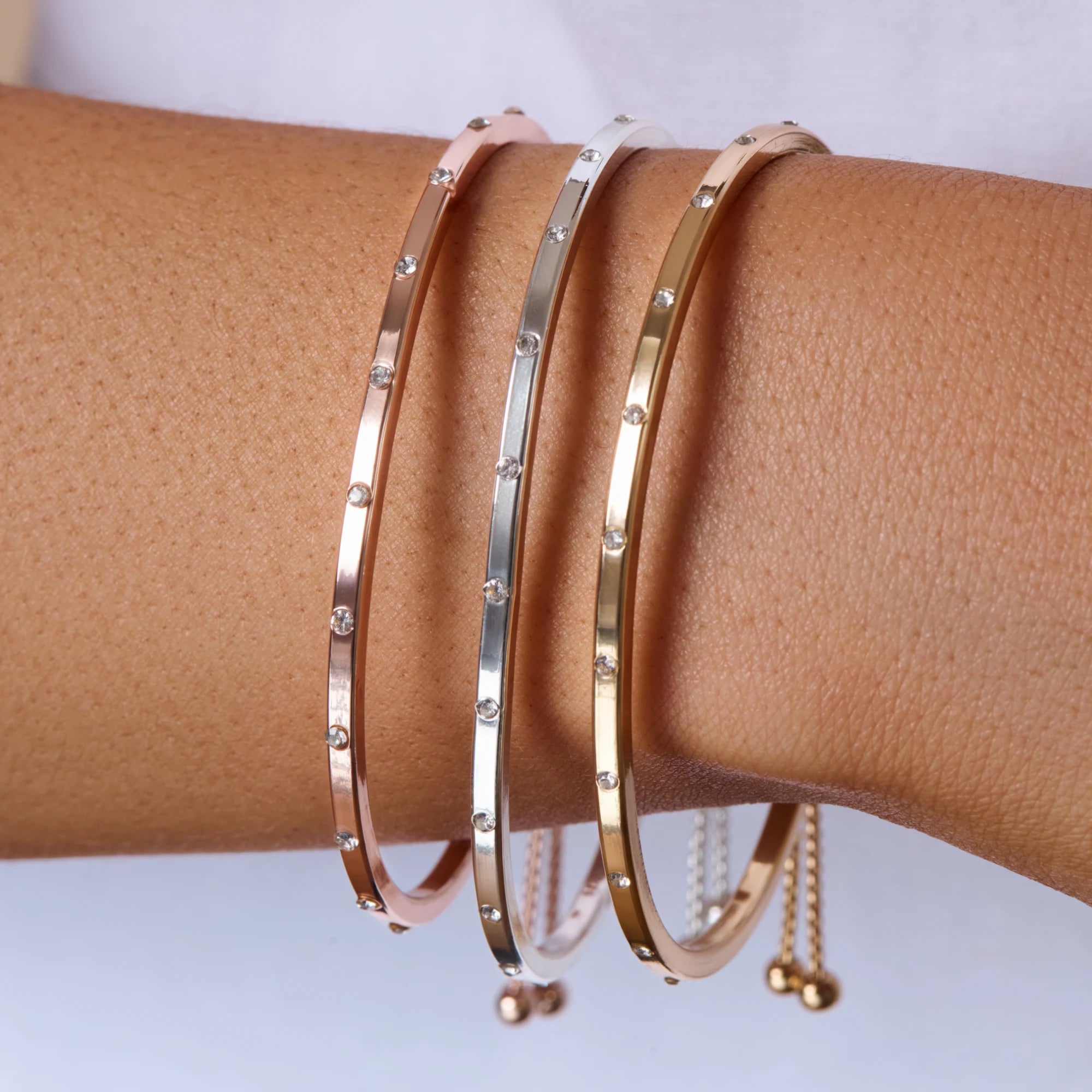 Three gold bracelets on a brown surface with a white background