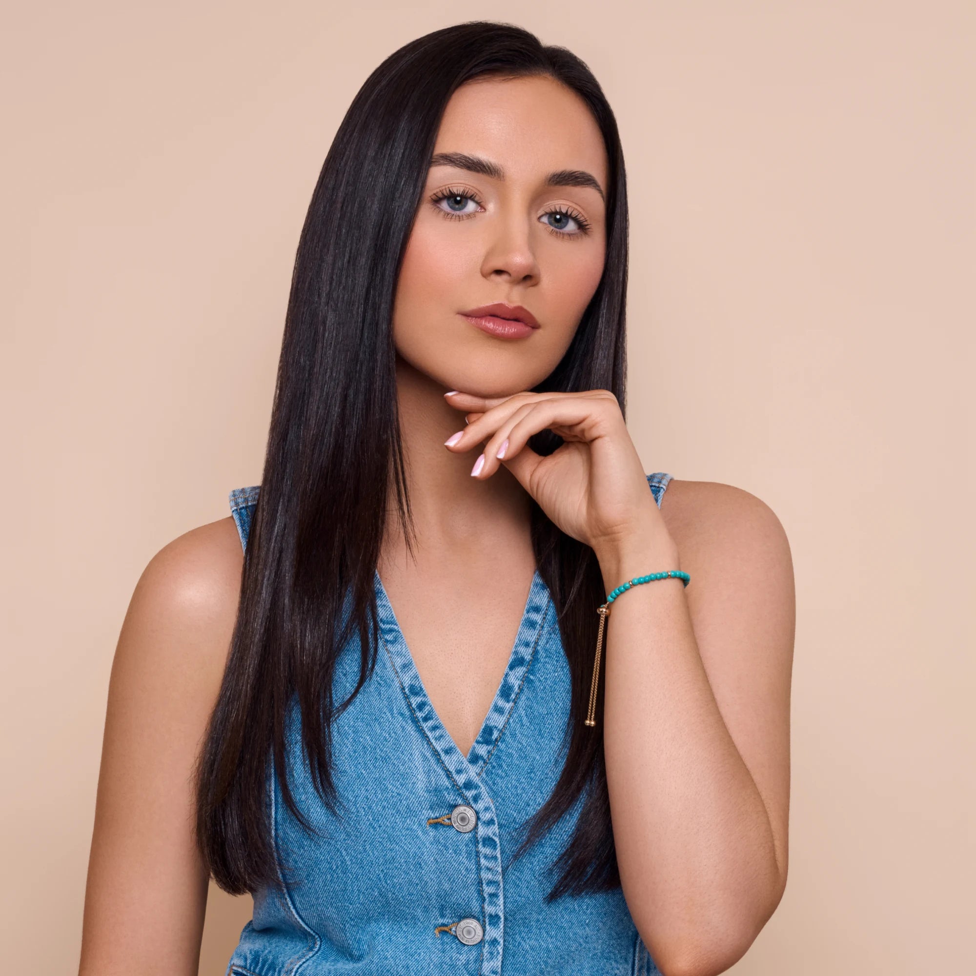 Woman wearing a blue denim dress against a beige background