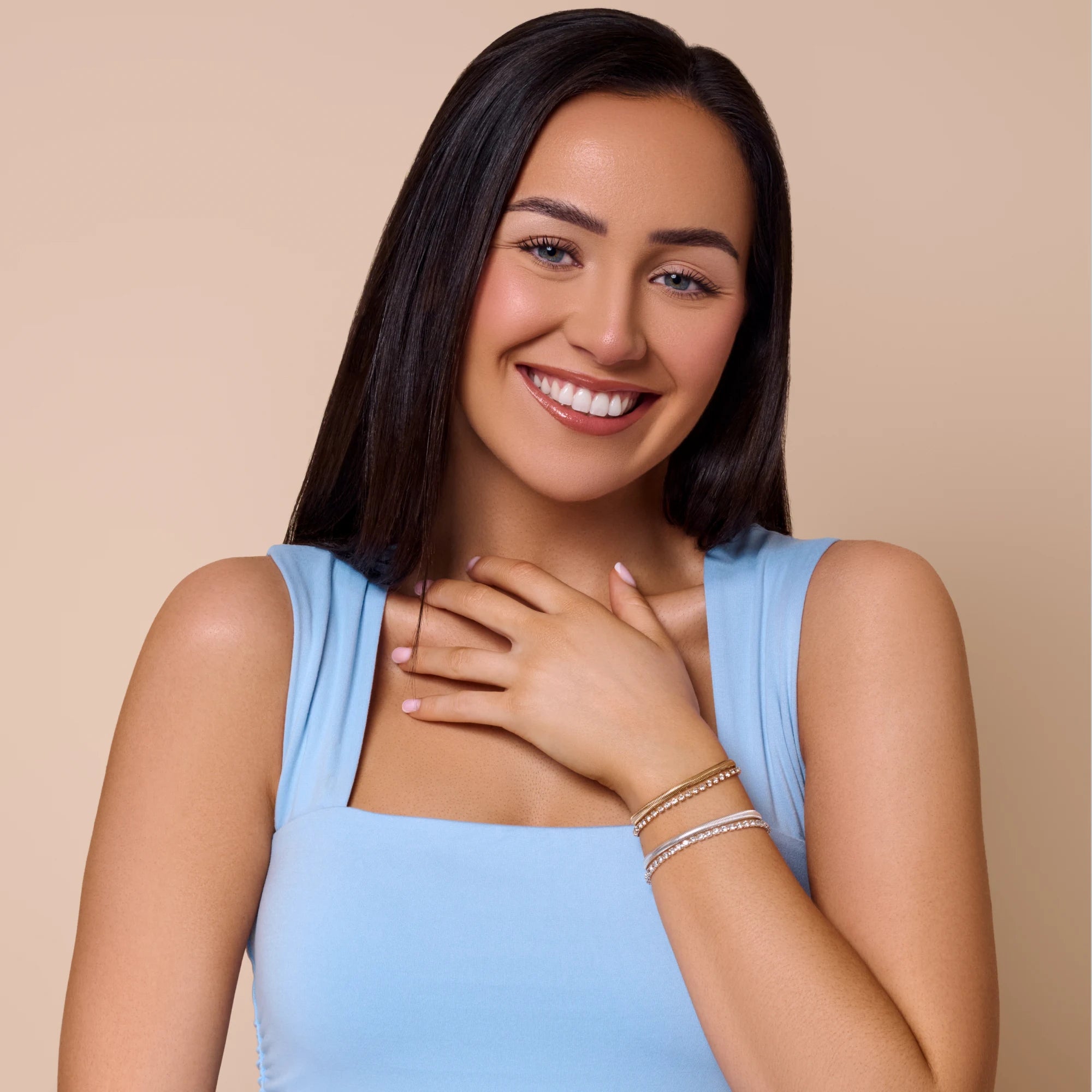 Woman wearing a light blue sleeveless top against a beige background