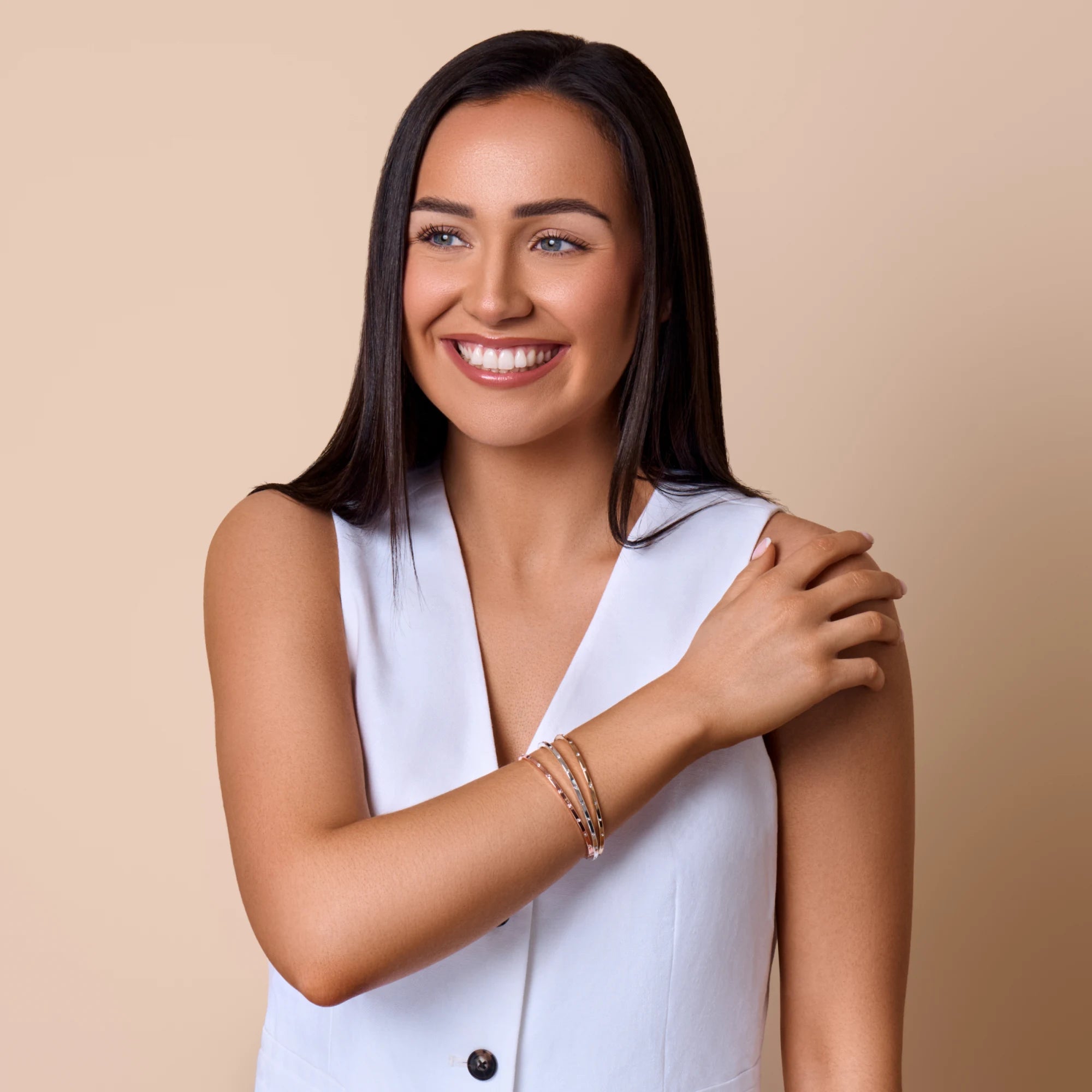 Woman wearing a white sleeveless top against a beige background
