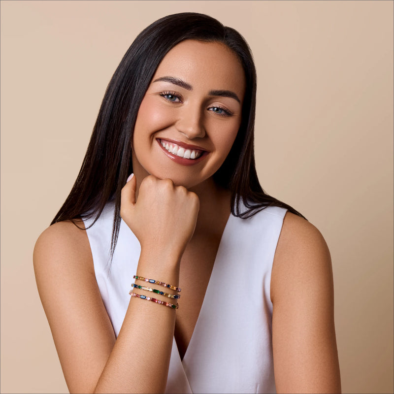 Woman wearing a white sleeveless top and colorful bracelets on a beige background
