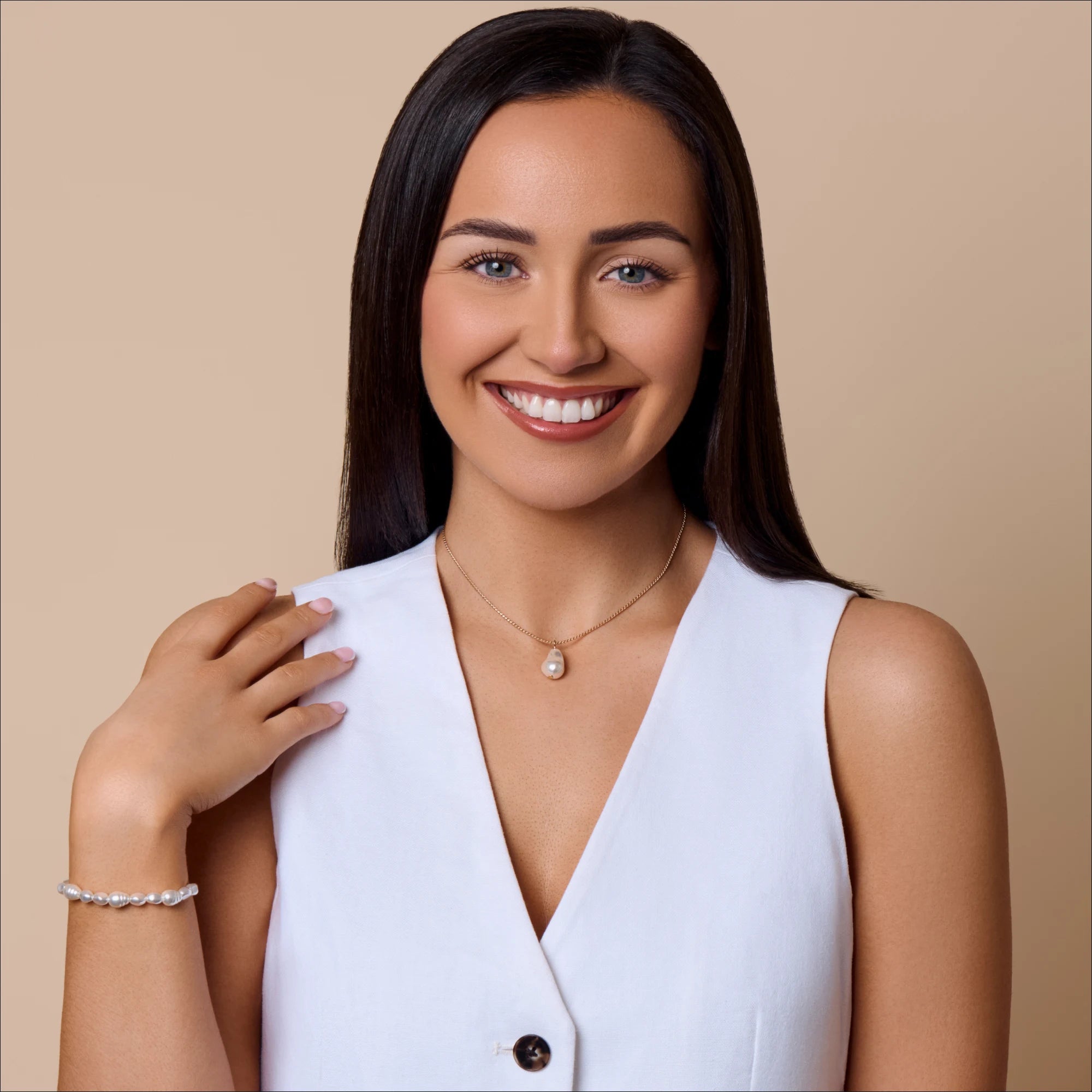 Woman wearing a white blouse with a necklace on a beige background