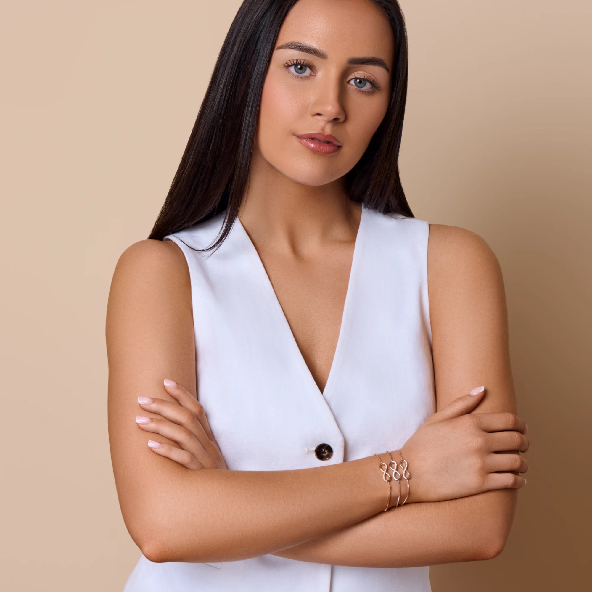 Woman wearing a white sleeveless top with a beige background
