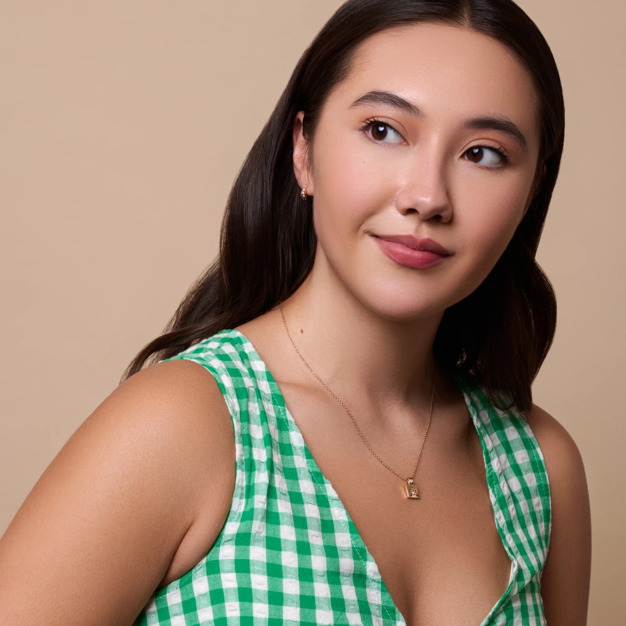 Woman wearing a green and white checkered dress against a beige background