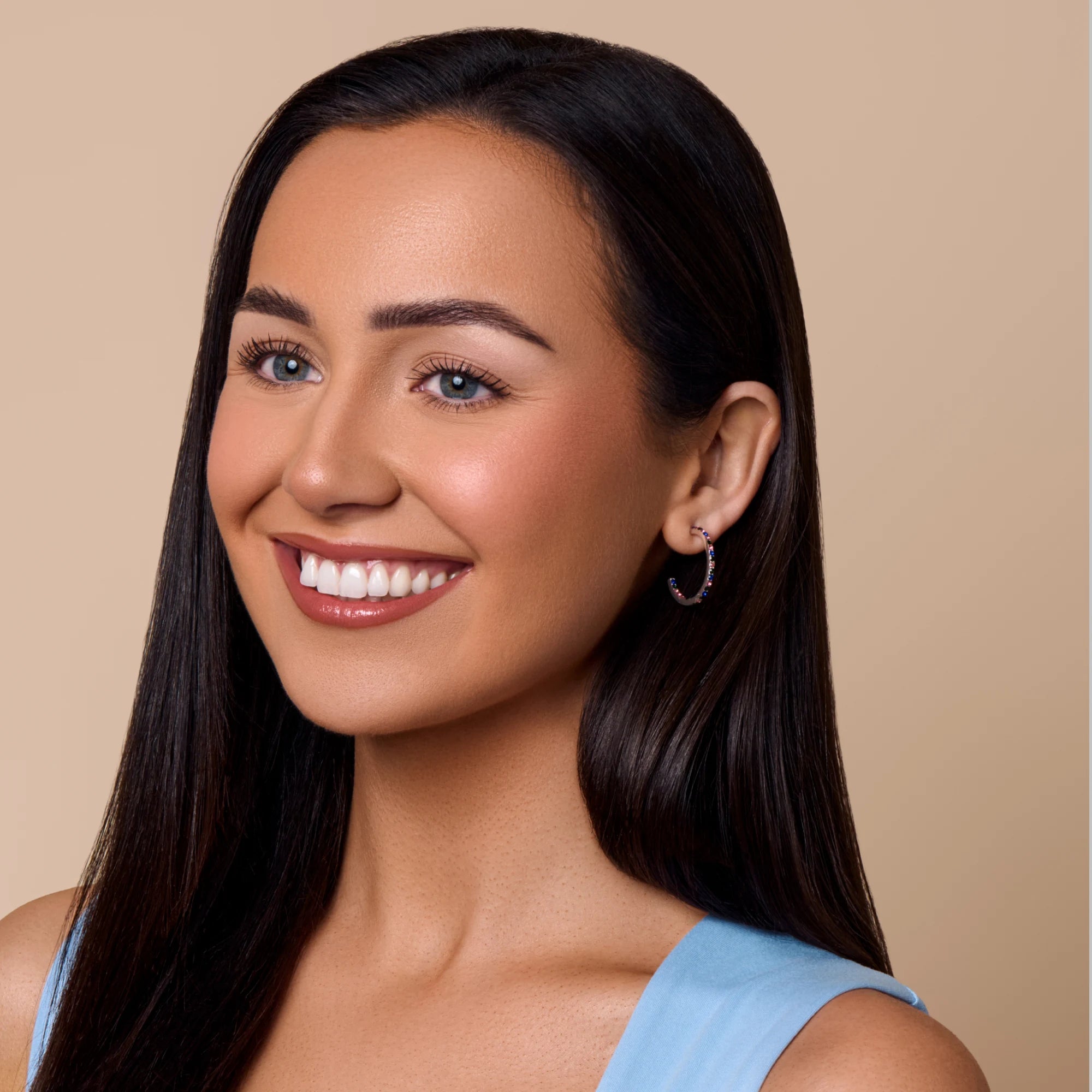 Woman with long dark hair wearing a blue top against a beige background