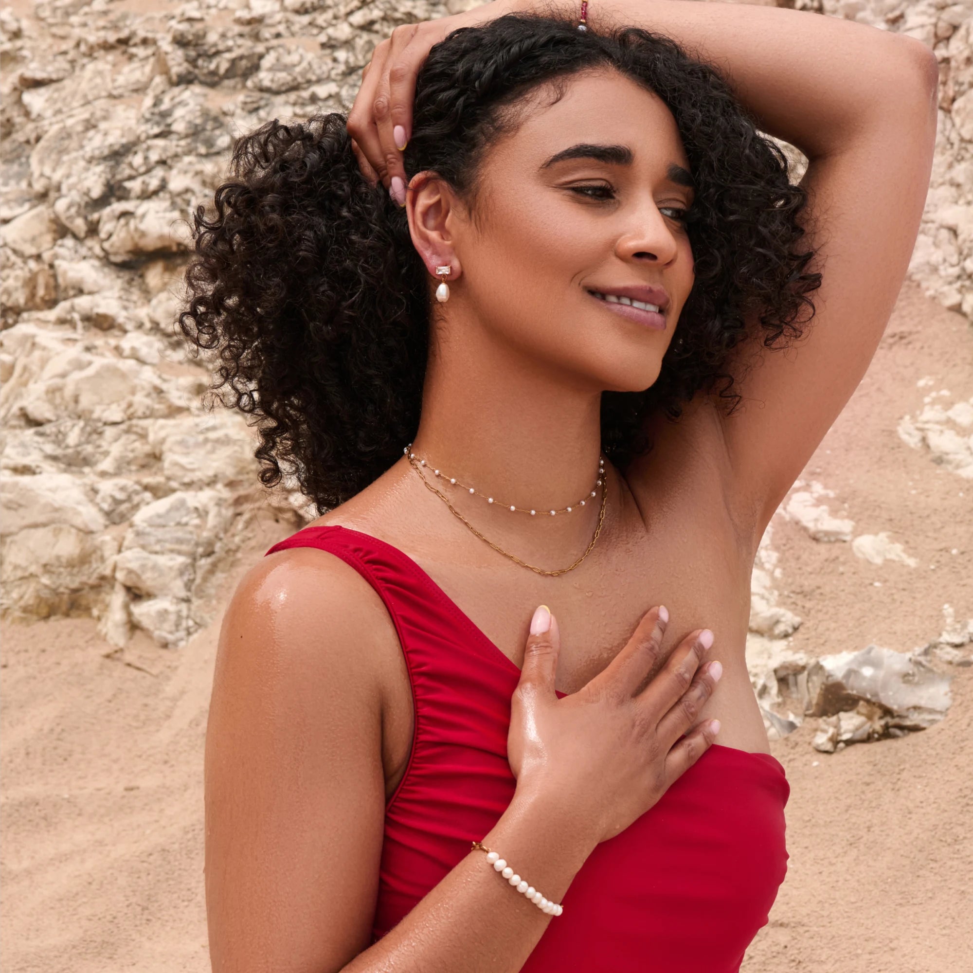 Woman in a red dress standing on a rocky beach