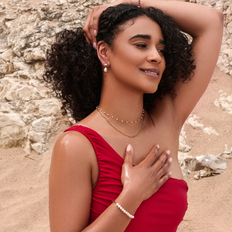 Woman in a red dress standing on a rocky beach