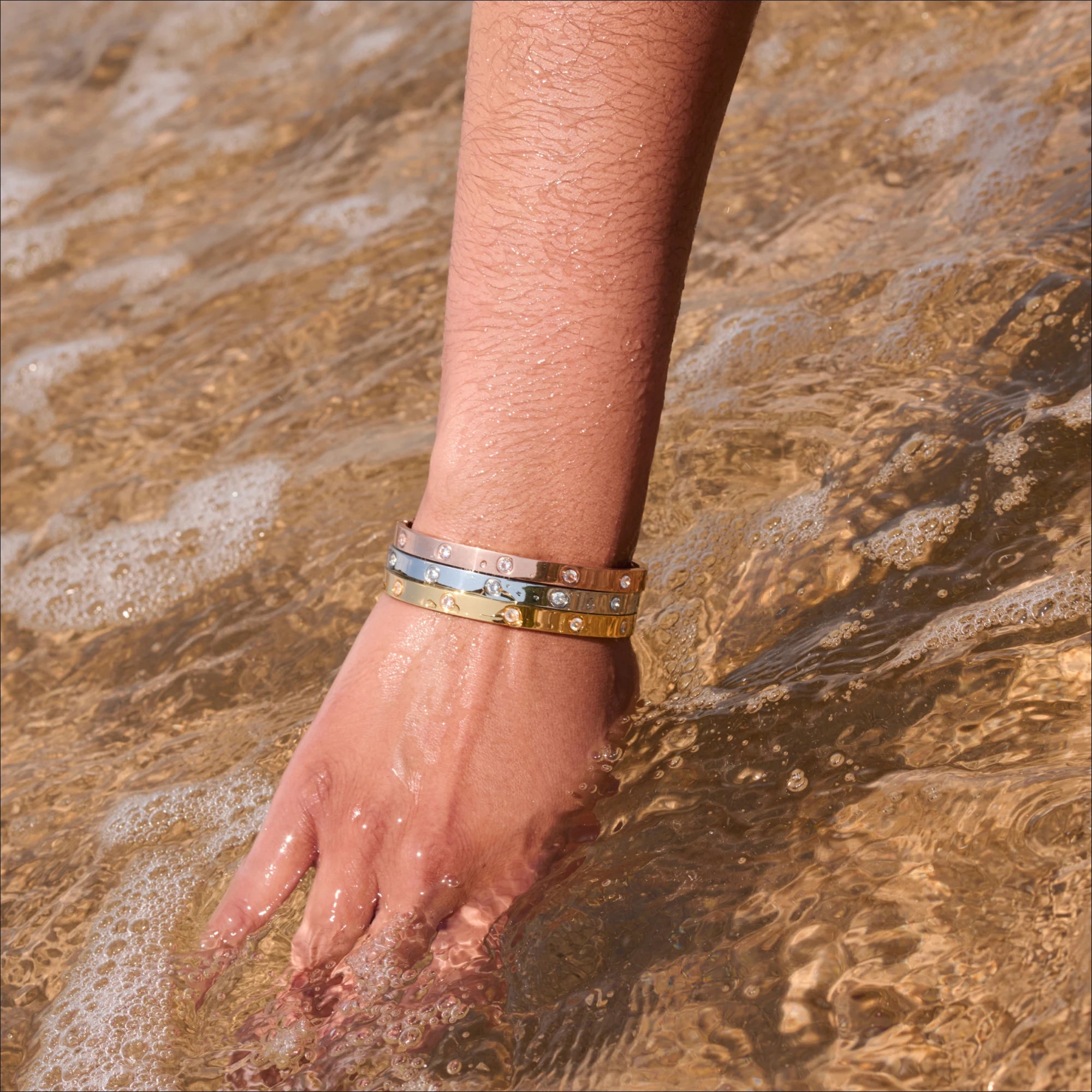 Hand with bracelets in shallow water
