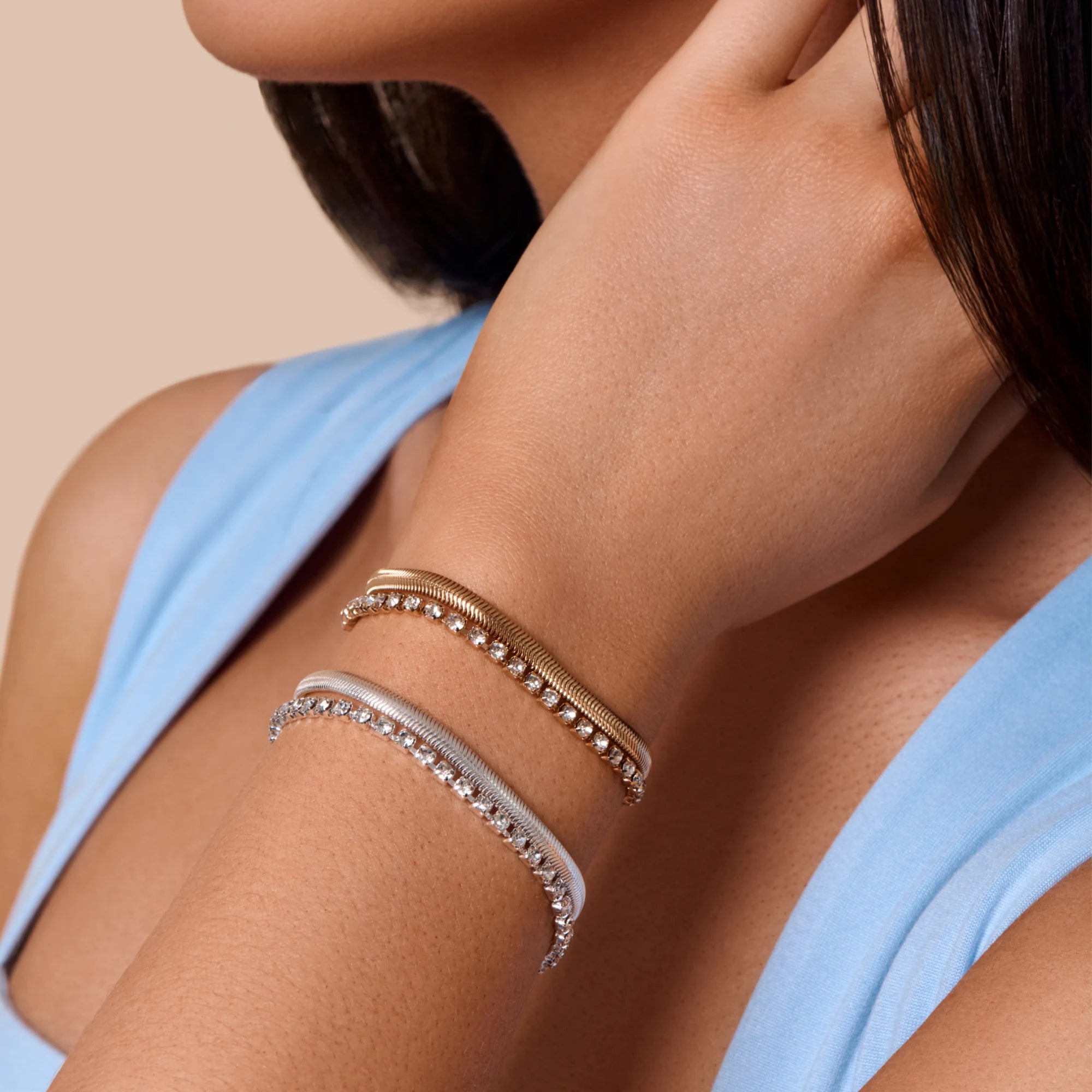Close-up of a woman's arm wearing two bracelets on a beige background