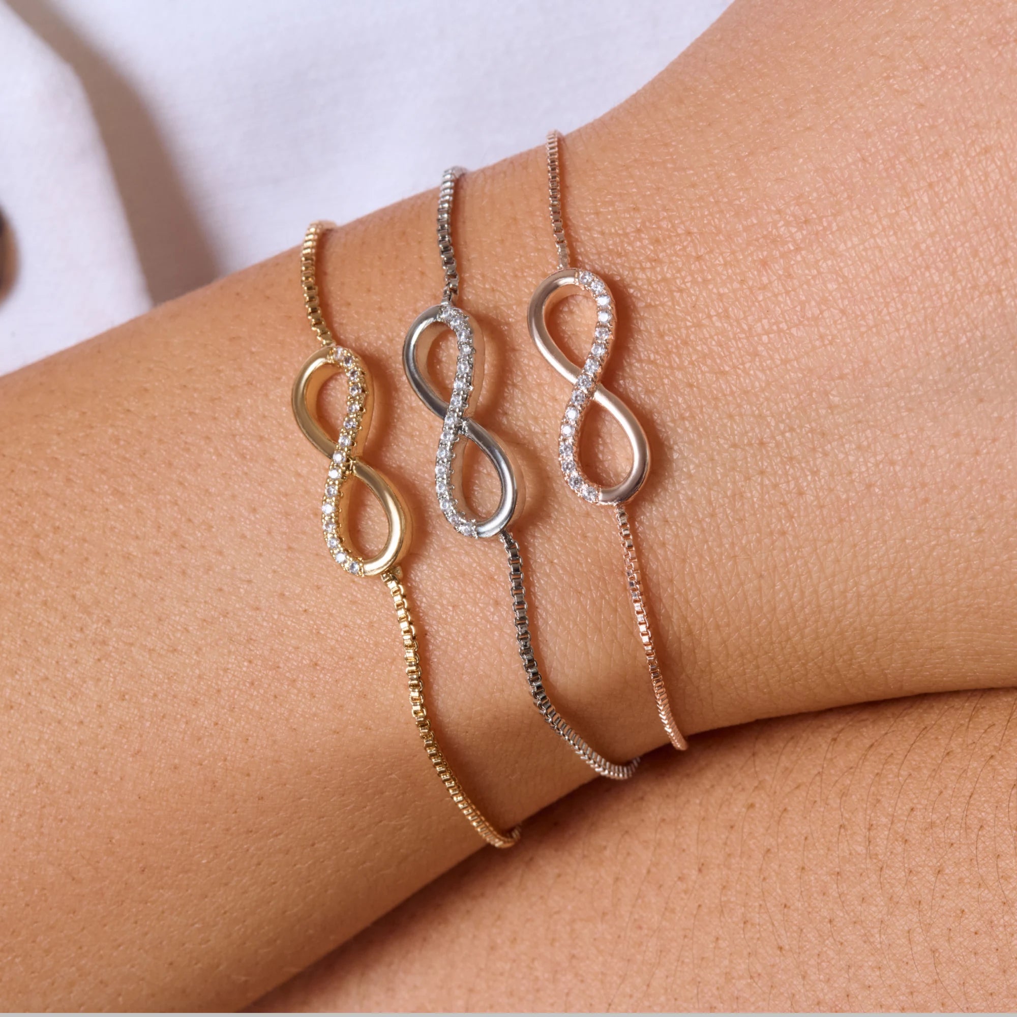 Three infinity bracelet on a wrist with a neutral background