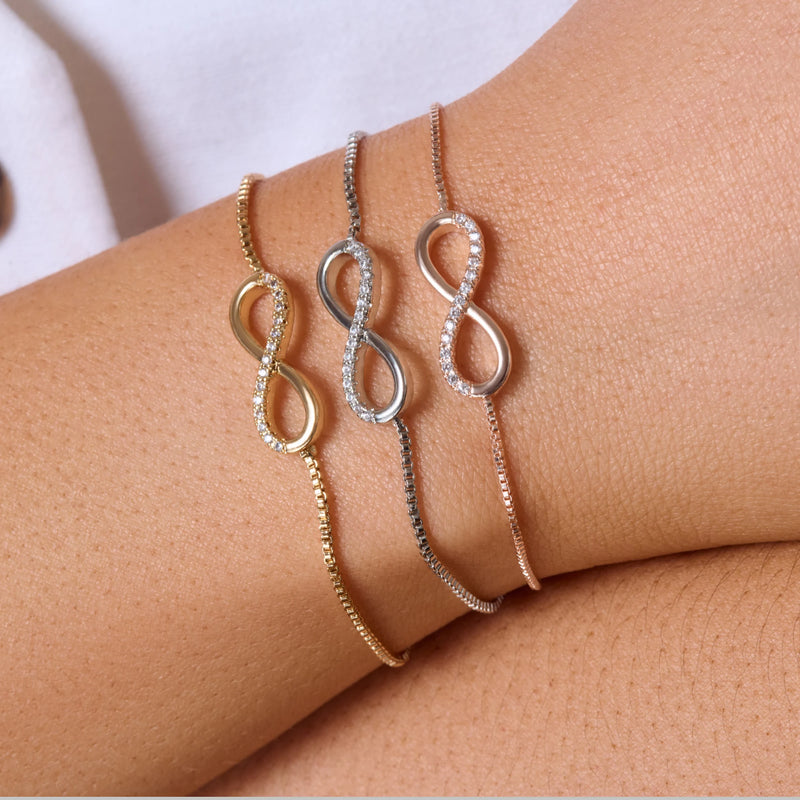 Three infinity bracelet on a wrist with a neutral background
